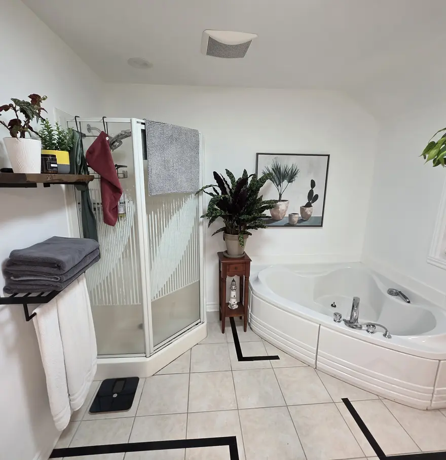 Avant : bain jacuzzi de coin et cabine de douche encadrée en céramique blanche.