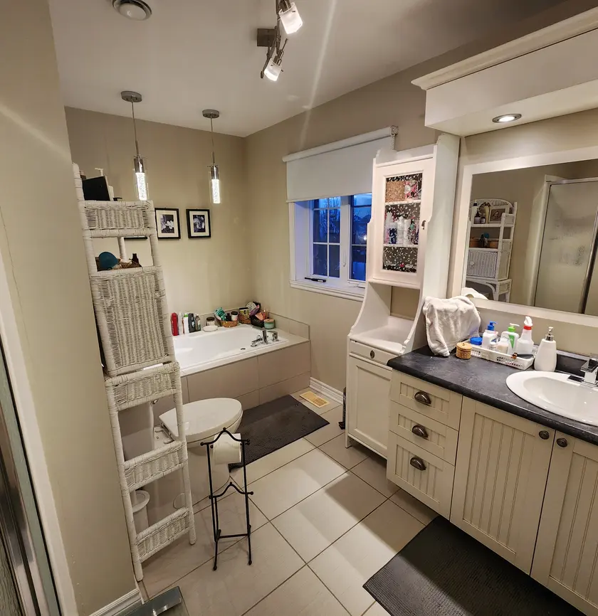 Avant : salle de bain beige encombrée avec bain encastré et vanité double vieillie.