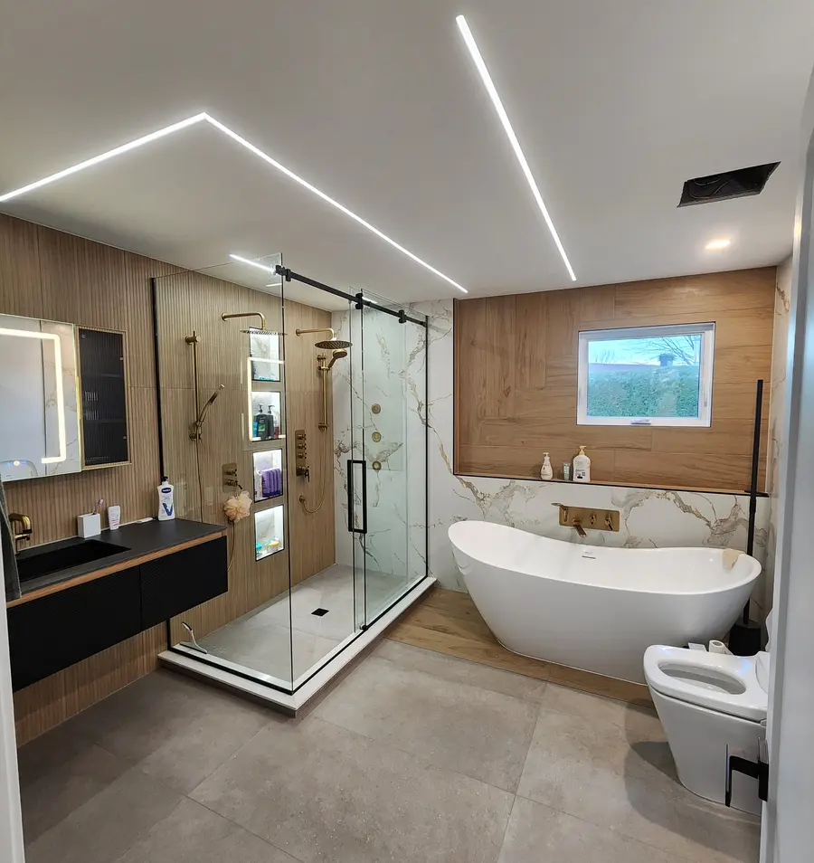 Salle de bain haut de gamme réalisée par Renovo Solutions : bain autoportant, douche vitrée, mur de bois et plafond au ruban DEL.